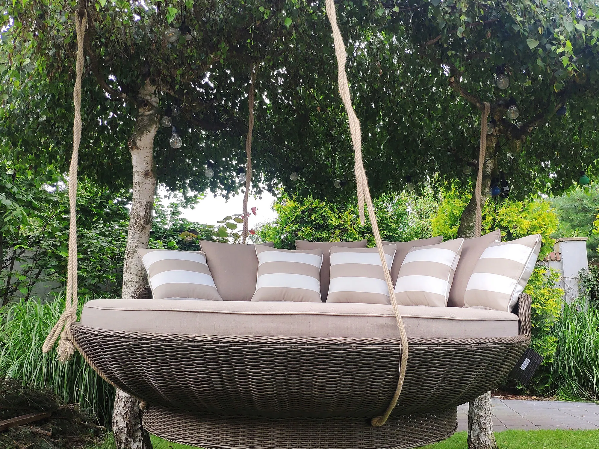 Wisząca leżanka KORSYKA brązowy mat — między drzewami w ogrodzie